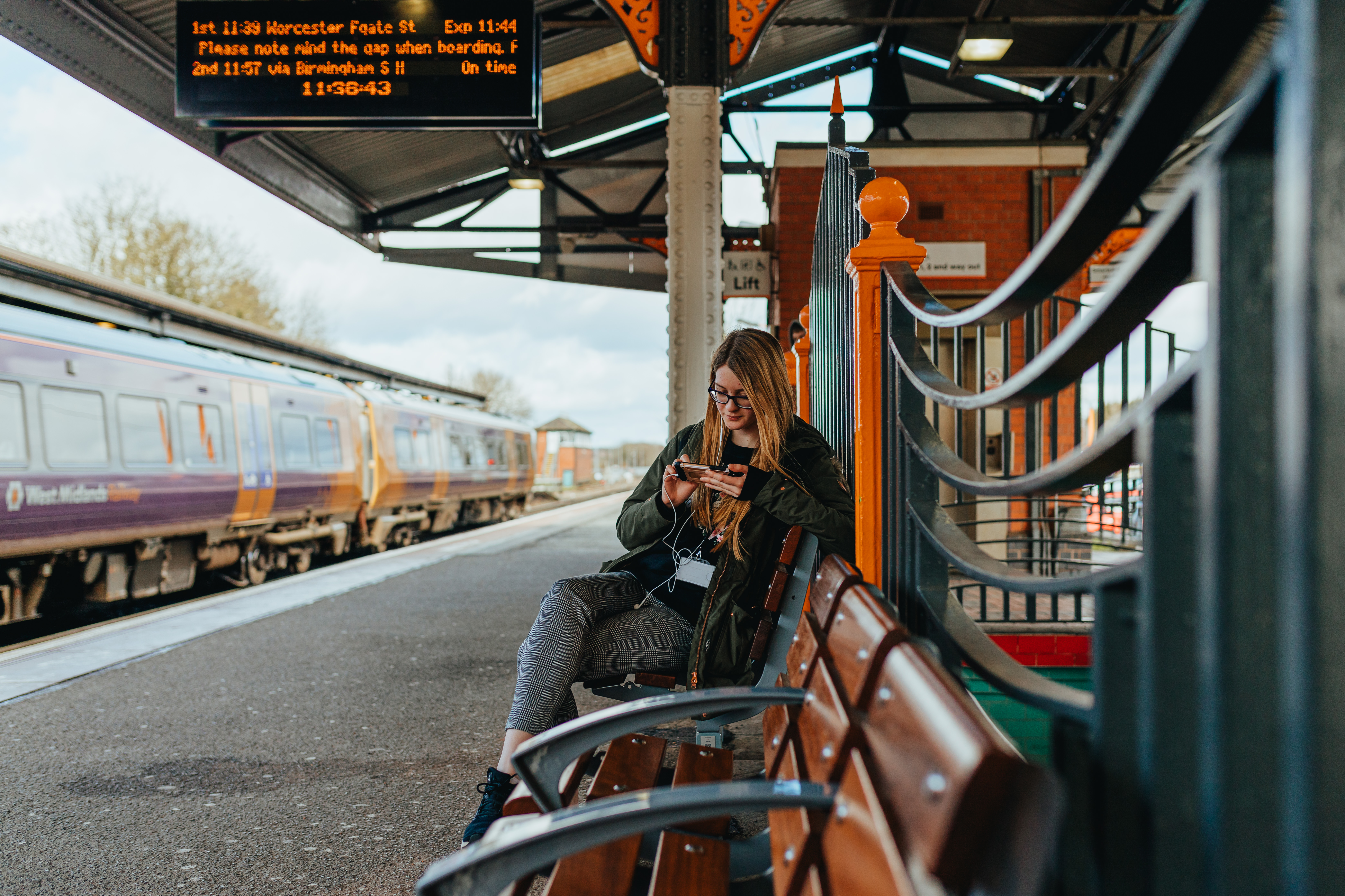 A woman sitting on a bench at a train station